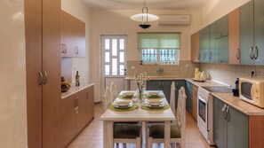 Una cucina con mobili in legno, un tavolo da pranzo apparecchiato con piatti, bicchieri e un vaso di fiori.