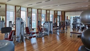 A gym with various exercise machines, large windows, and a wooden floor. - Luxury Vacation Home Nr Metro DWTC (Dubai)
