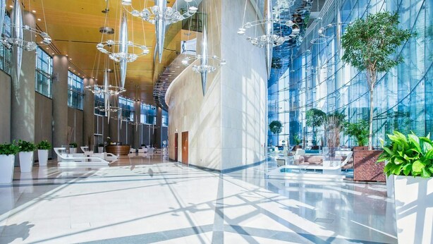 A spacious lobby with modern furniture, a central staircase, and large windows allowing natural light. - Luxury Vacation Home Nr Metro DWTC (Dubai)