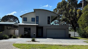 Une maison moderne à deux étages, dotée d’un garage, d’une allée couverte et d’une pelouse bien entretenue.