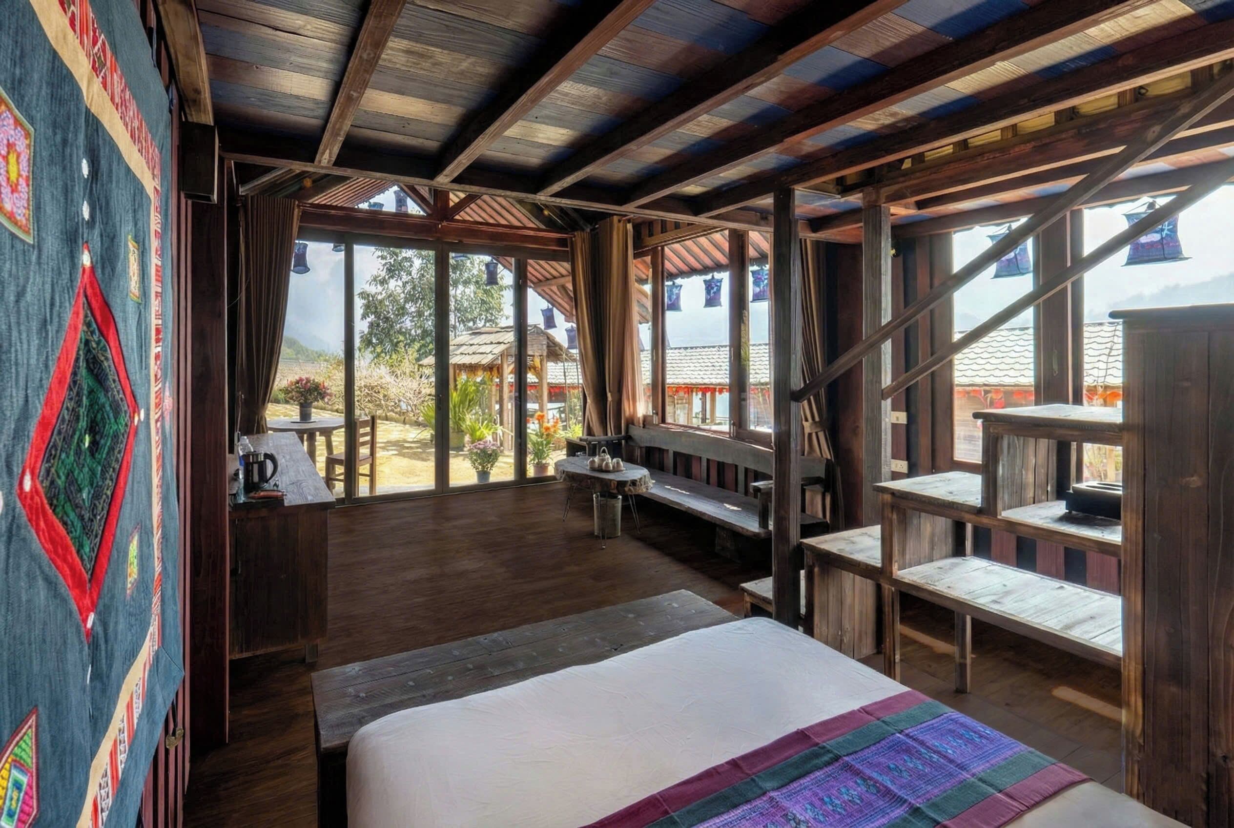 A rustic room with a bed, wooden benches, and a view of the outdoors.