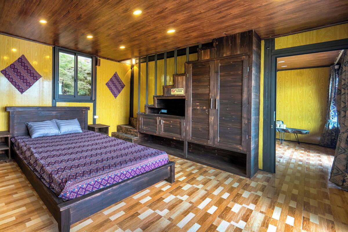 Een slaapkamer met een houten bed, een inbouwkast en uitzicht door een open deur.