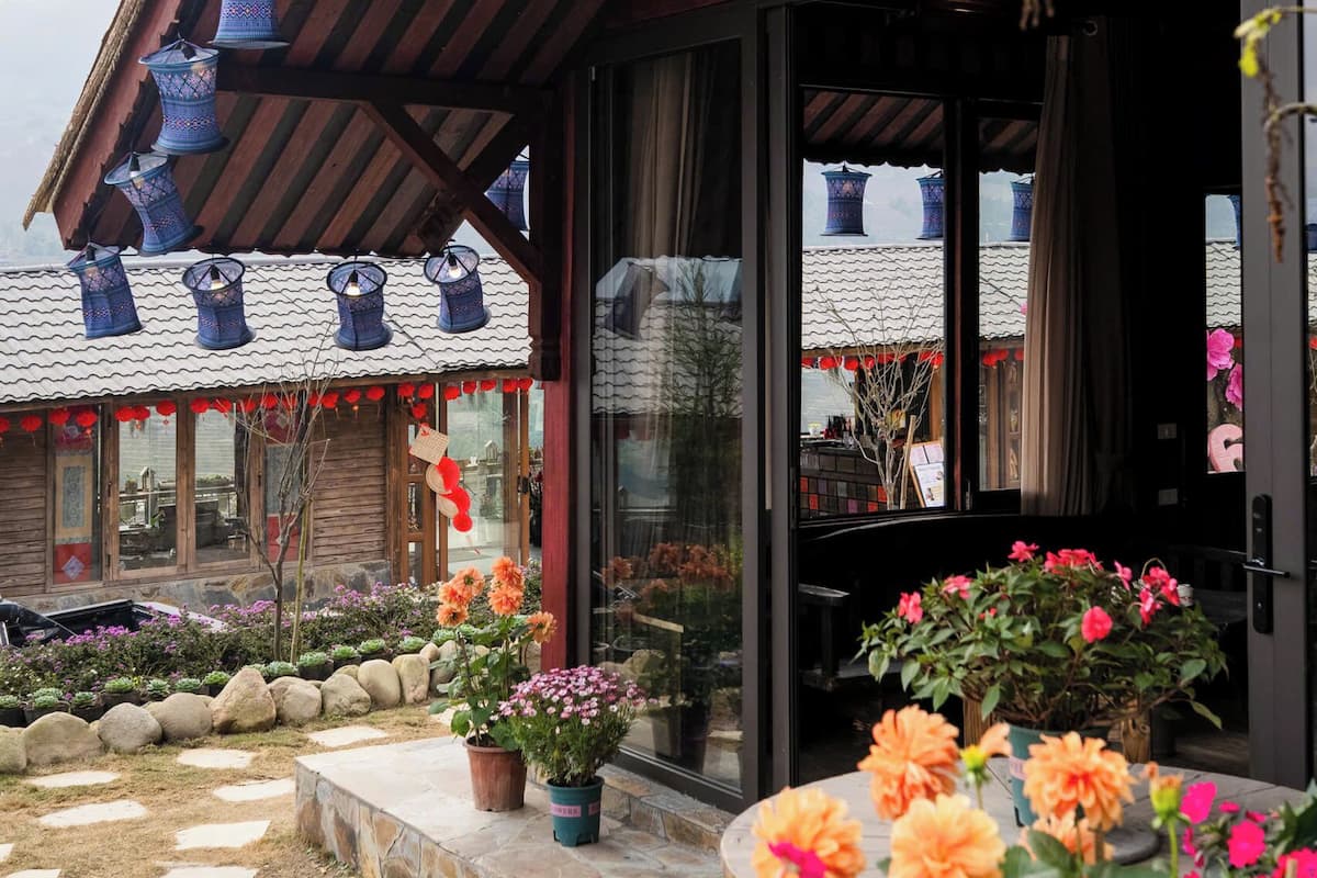 Een traditioneel gebouw met een pannendak, een houten veranda en hangende blauwe lantaarns.