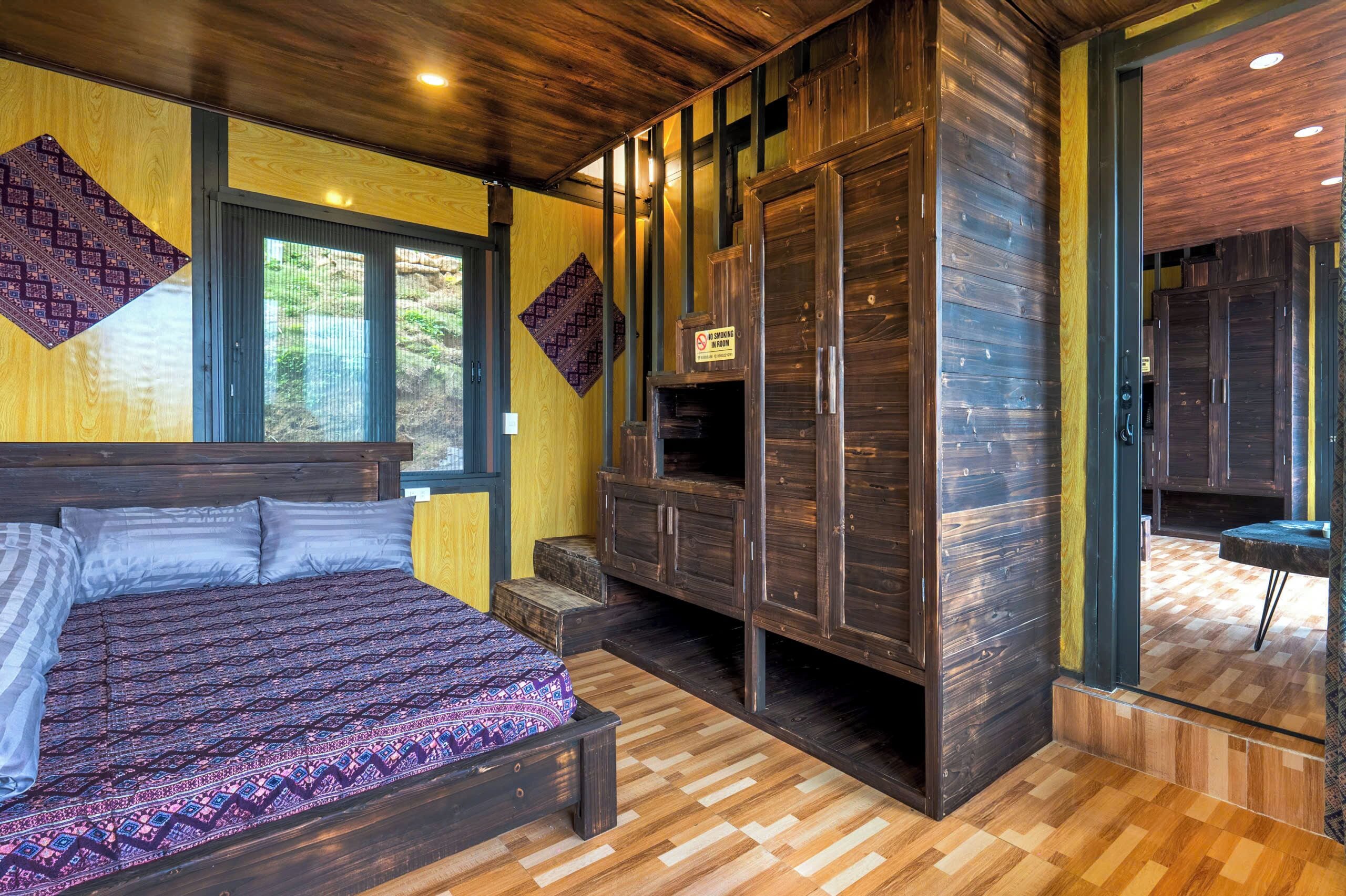 Une chambre avec un grand lit, une armoire intégrée et une vue sur l’extérieur grâce à une porte vitrée.