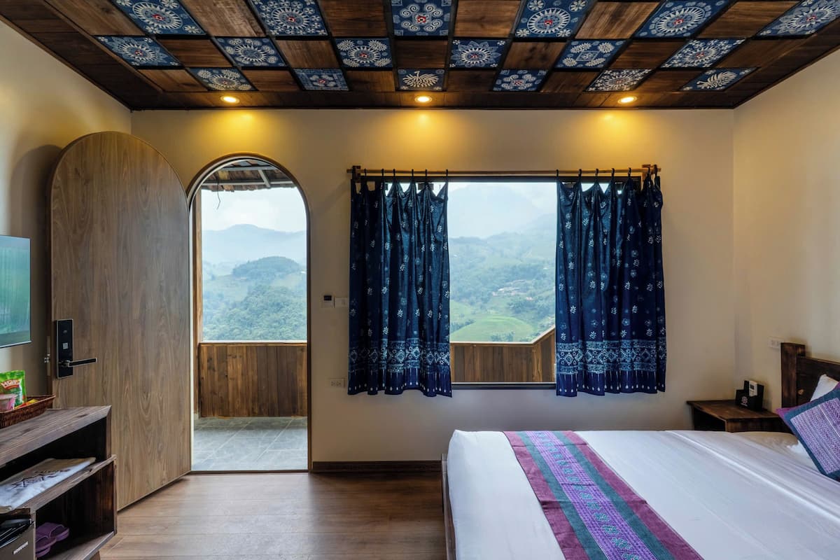 Een slaapkamer met een bed, een houten kledingkast, een televisie en een raam met gordijnen.
