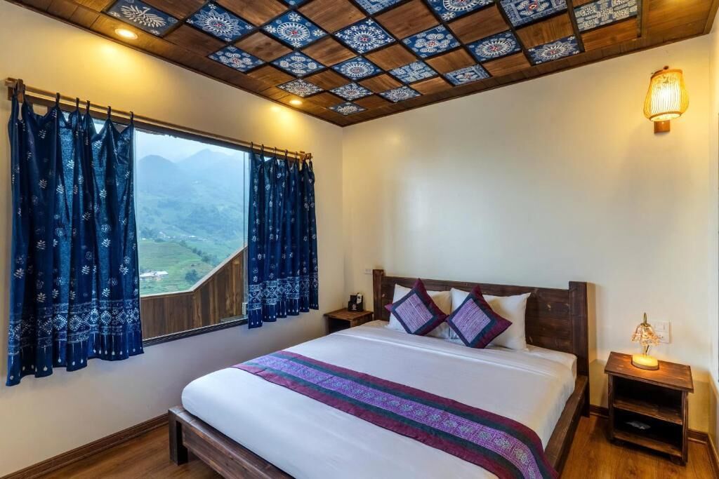 Un dormitorio con una cama grande, una mesita de noche, una lámpara y vistas al exterior.