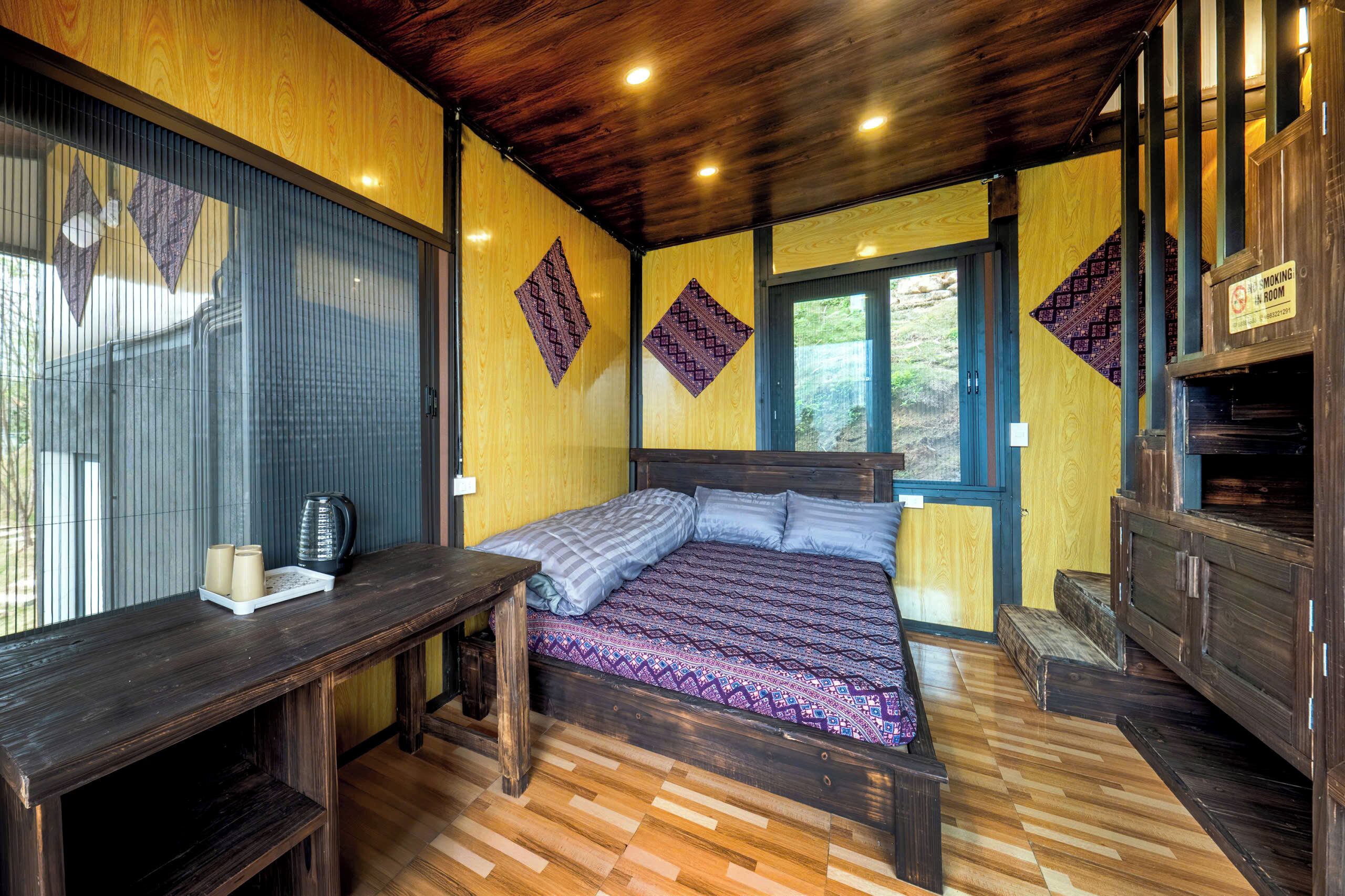 A room with a bed, a wooden desk, a window, and a sign indicating a moving room.