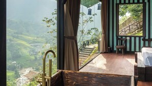 A room with a large window offering a view of terraced fields. - Sapana Mountain Retreat (Sa Pa)