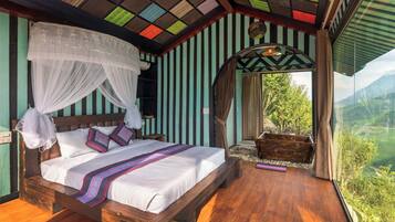 A bedroom with a wooden bed, a canopy, and a view of a lush landscape.