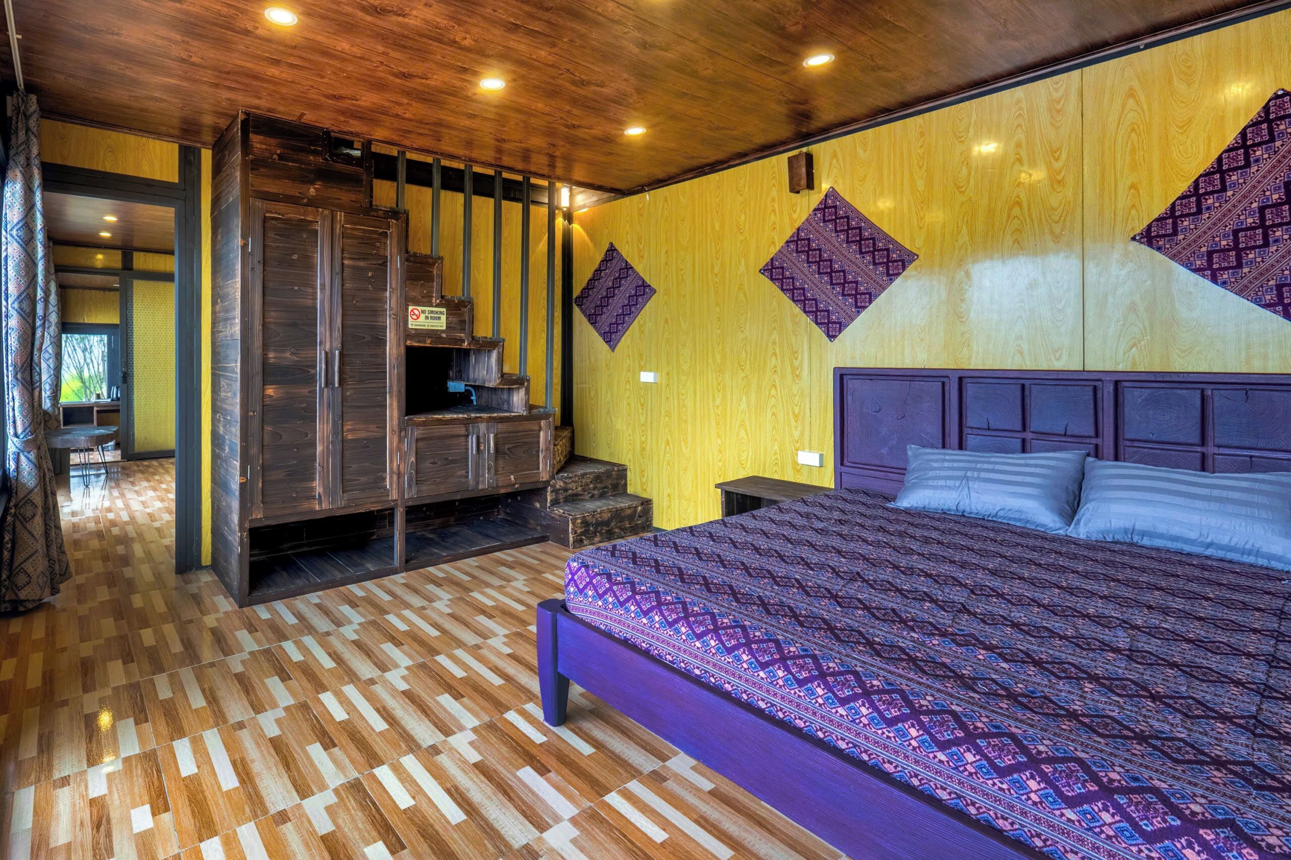 Een slaapkamer met een groot bed, een houten kledingkast en een behang met een patroon.
