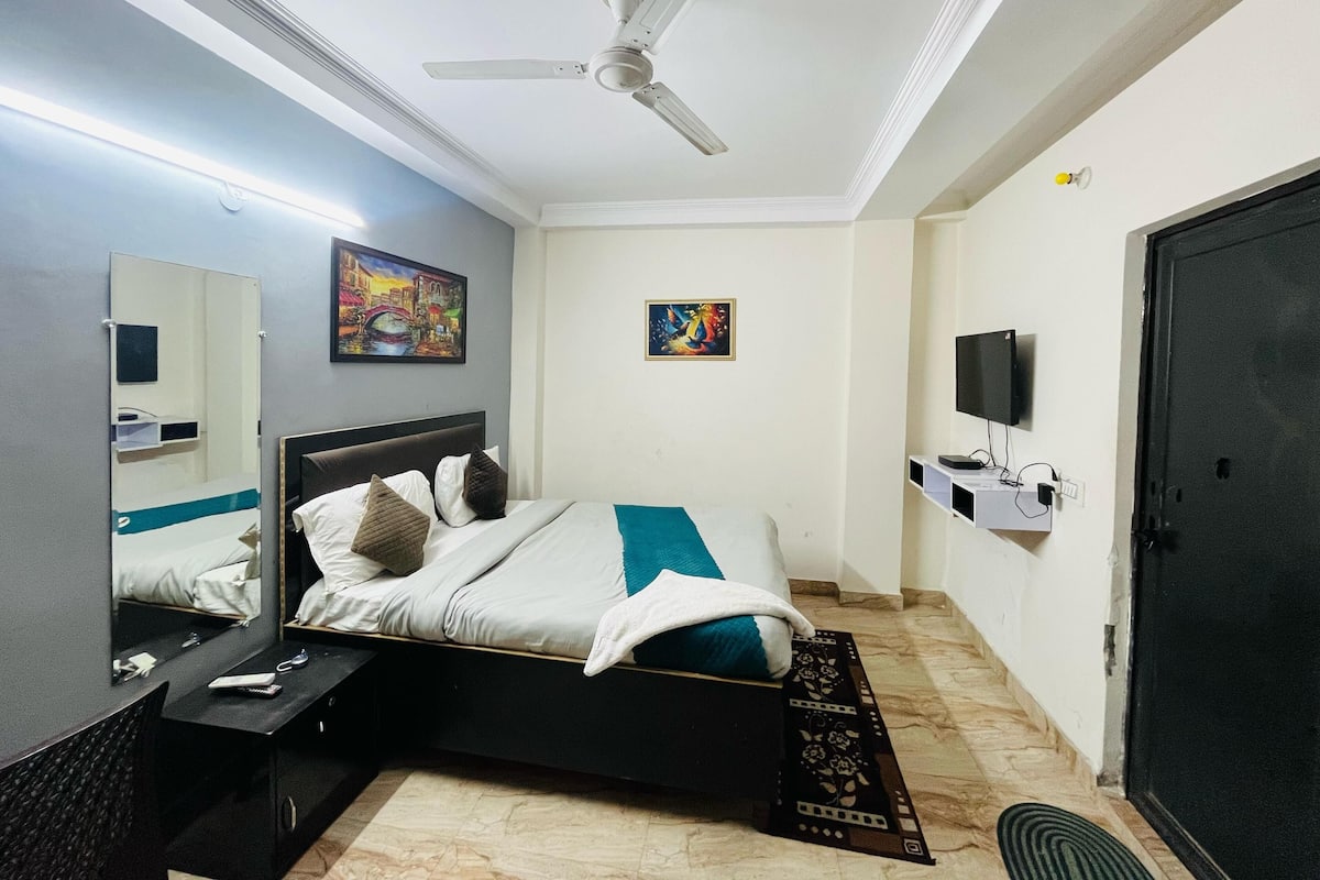 Ein Hotelzimmer mit Bett, Deckenventilator, Fernseher und Kunstwerken an den Wänden.