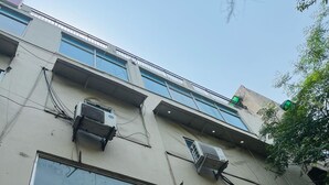 A building with multiple air conditioning units, large windows, and a sign for 'Rapper's Cafe'. - Roomshala Hotel South Embassy (New Delhi)