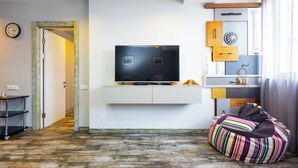 A modern living room with a flat-screen TV on a white console, a striped bean bag, and a wooden cabinet with decorative items. - Apartment by Luxe Group SN400 (Yerevan)