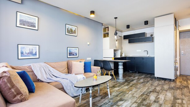 A modern living room with a sofa, a dining table, and a kitchen area with a sink and cabinets. - Apartment by Luxe Group SN400 (Yerevan)