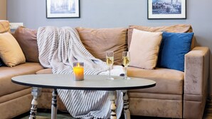 A cozy living room with a beige sofa, a round table, and two framed pictures on the wall. - Apartment by Luxe Group SN400 (Yerevan)