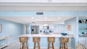 Una cucina moderna con isola centrale, mobili bianchi e paraschizzi blu.