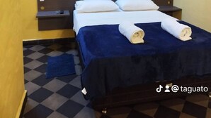 A single bed with a dark headboard, white pillows, and a blue bedspread.