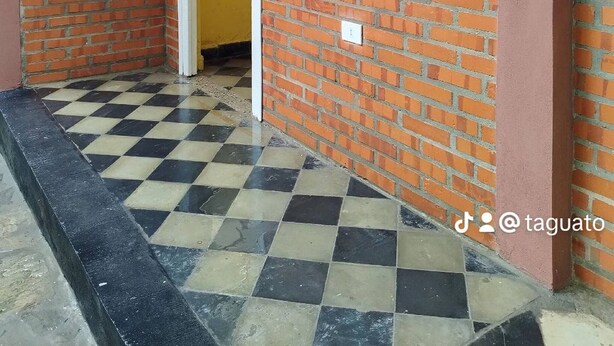 A brick exterior with a white-framed window, a yellow door, and a checkered floor.