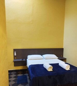 A single bed with a dark headboard, white pillows, and a blue bedspread.