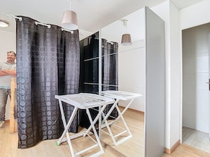 Una habitación con suelo de madera, una mesa plegable blanca y un espejo.