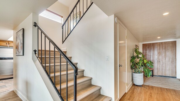 A staircase with wooden steps and black railings, leading to a room with a wooden door and a potted plant. - Mtn-View Townhome w/ Pools: 5 Mi to Sabino Canyon! (Tucson)