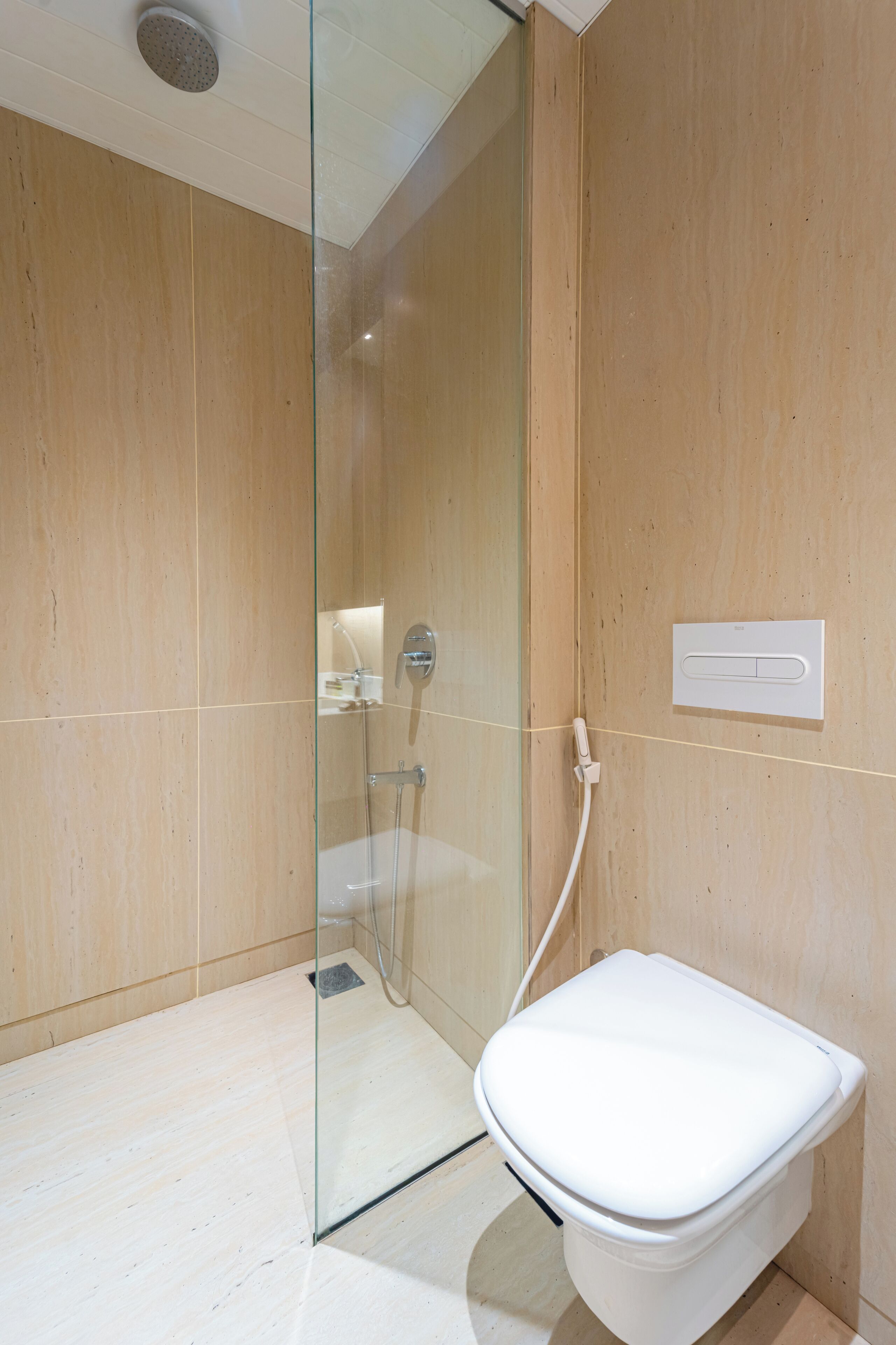 Un baño moderno con ducha de vidrio, inodoro blanco y pared de madera.