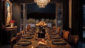 A formal dining room with a long table set for a meal, a chandelier, and a view of the night sky. - Iconic 6BR Desert Retreat w/ Pool, Pickleball & Fire Pit Joshua Tree Mansion by Avantstay (Joshua Tree)