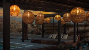 A poolside area with wicker pendant lights, lounge chairs, and a view of the mountains. - Iconic 6BR Desert Retreat w/ Pool, Pickleball & Fire Pit Joshua Tree Mansion by Avantstay (Joshua Tree)