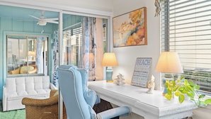 A room with a white sofa, a blue chair, a small table with a lamp, a painting, and a sign on the wall. - Steps From the Sand Bright Coastal Stay w/ Pool Access Coastal Hideaway by Avantstay (Destin)