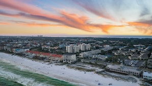 A coastal town with beachfront properties, a bridge in the distance, and a sunset sky. - Steps From the Sand Bright Coastal Stay w/ Pool Access Coastal Hideaway by Avantstay (Destin)