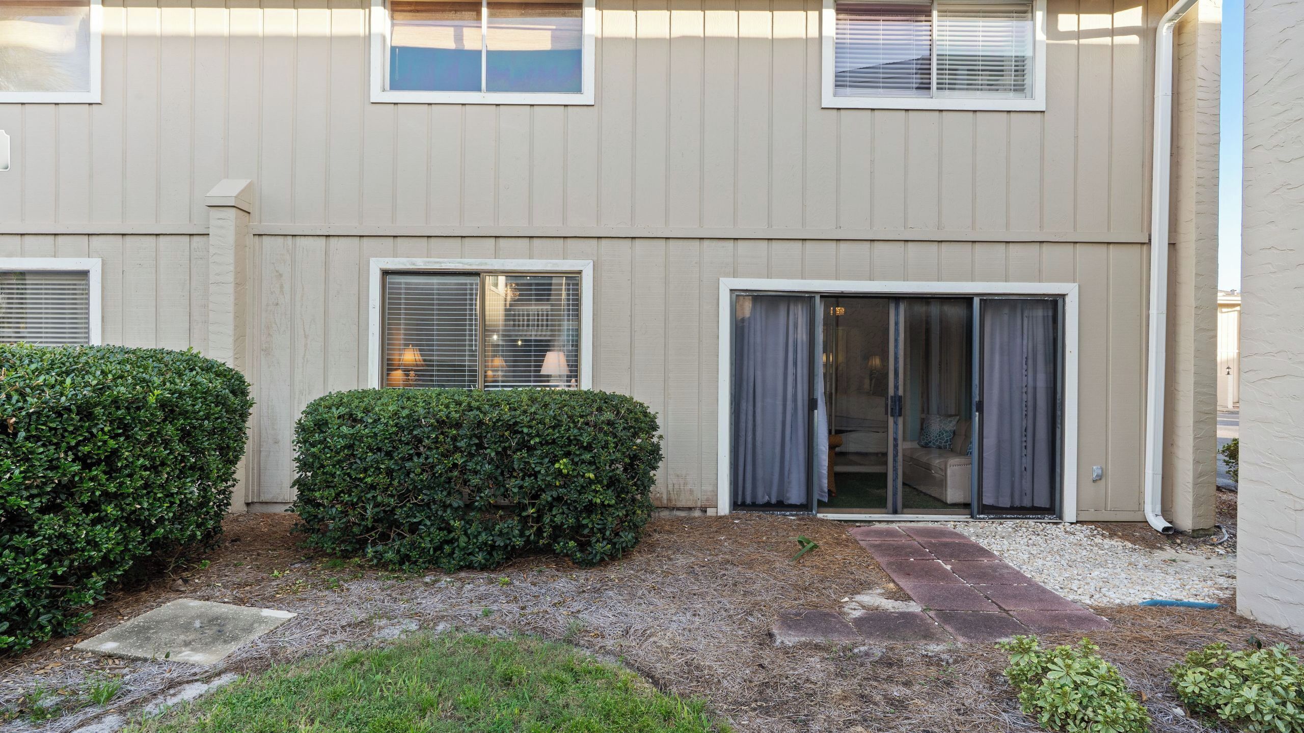 A building with a flat facade, large windows, and a sliding glass door leading to an interior space.