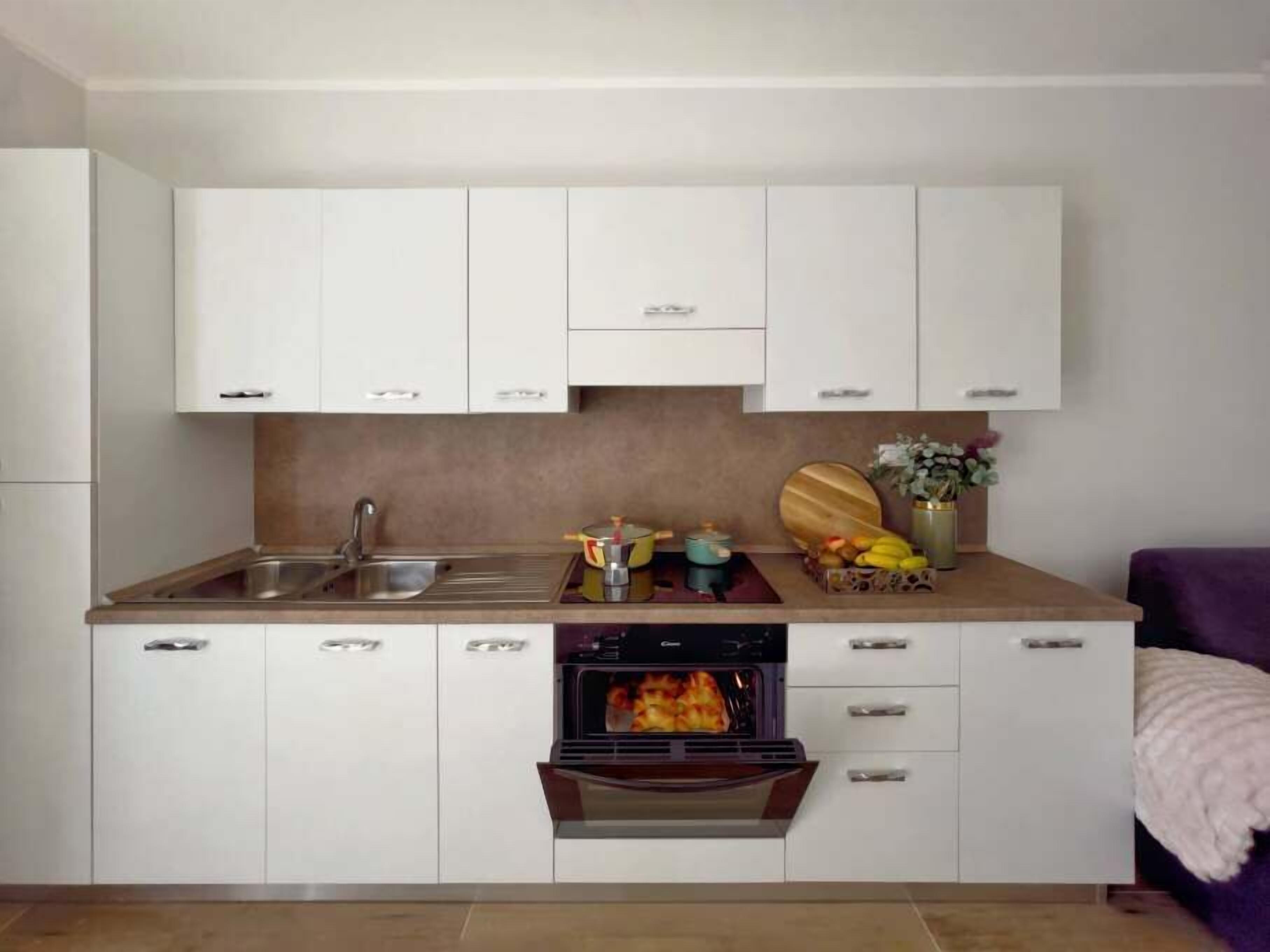 A modern kitchen with white cabinets, a built-in oven, and a countertop with various kitchen items.