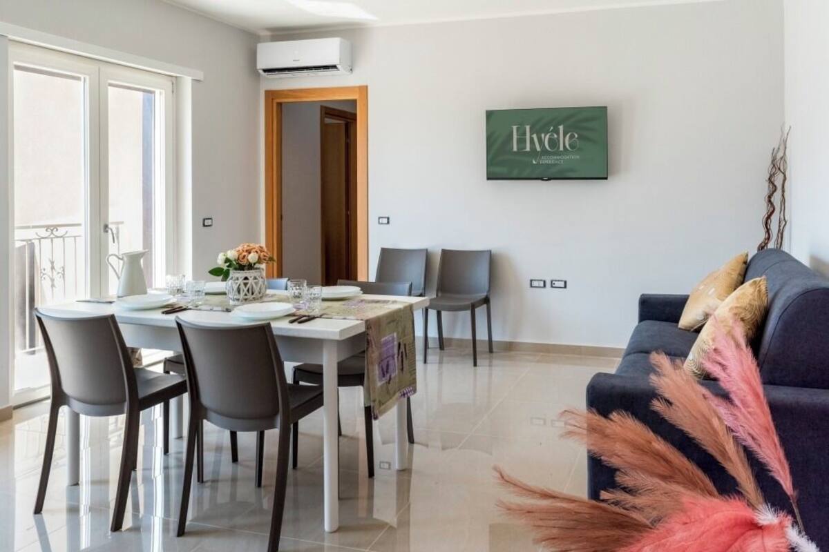 Un salon moderne comprenant un coin repas, un canapé et un téléviseur fixé au mur.
