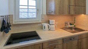 Eine Küche mit Einbauherd, einer Kaffeemaschine, einem Spülbecken und Holzschränken.