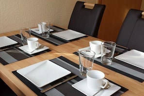 A neatly set dining table with black and white placemats, clear glasses, and white plates.