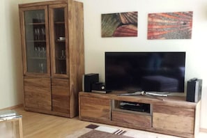 Un salon avec un meuble en bois, un téléviseur à écran plat et deux tableaux abstraits accrochés au mur.
