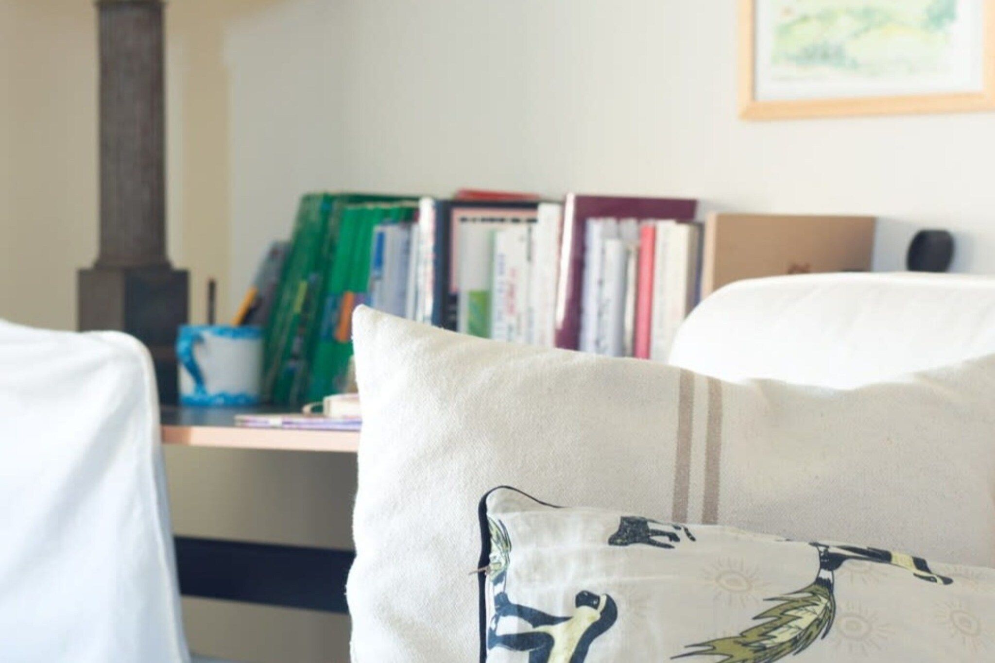 A room with a bookshelf, a fireplace, and a couch with patterned cushions.