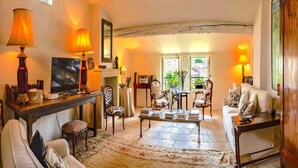 A cozy living room with a fireplace, a television, and a comfortable seating area. - Heated Pool Apartment in Uzes (Uzès)