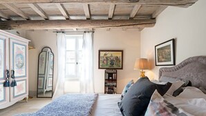 A bedroom with a bed, a dresser, a mirror, a bookshelf, and a painting on the wall. - Heated Pool Apartment in Uzes (Uzès)