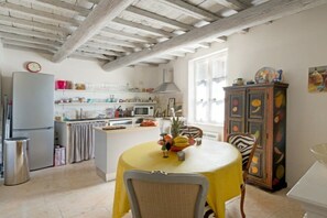 A kitchen with a dining table, chairs, a refrigerator, and a cabinet.
