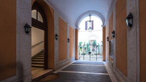 Ein Korridor mit Treppe, Rundbogenöffnungen und Blick auf einen Innenhof.
