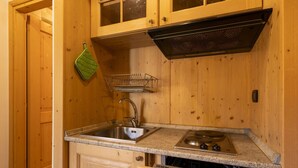 A compact kitchen with wooden cabinets, a stainless steel sink, a dishwasher, and a stove.