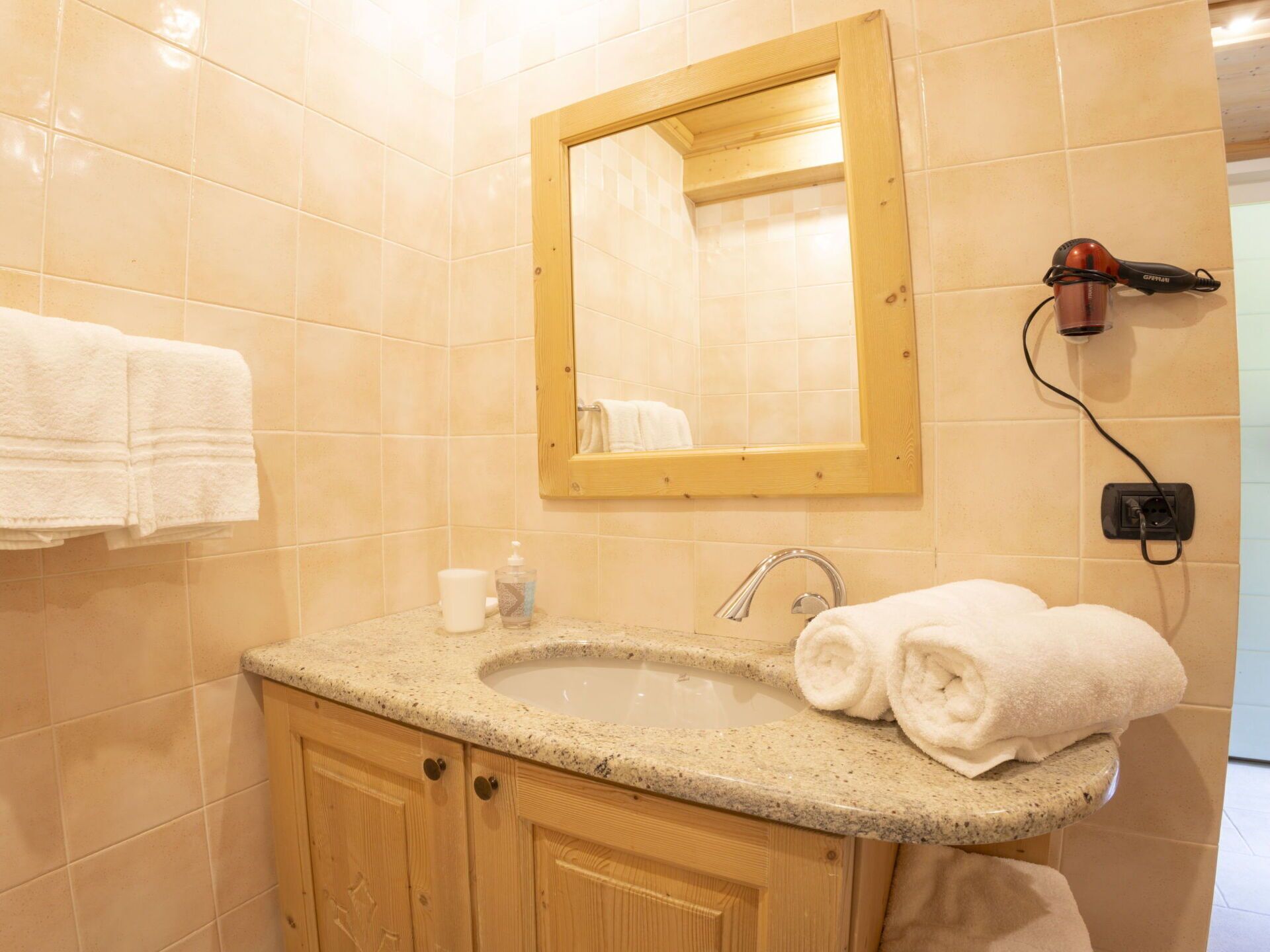 A bathroom with a sink, mirror, towel rack, and a hairdryer on the wall.