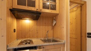 A wooden kitchen with a stove, sink, and cabinets.