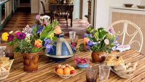 A dining table with a variety of flowers in vases, bread, fruits, and glasses. - Maniero in Maremma, luxury villa (Montiano)