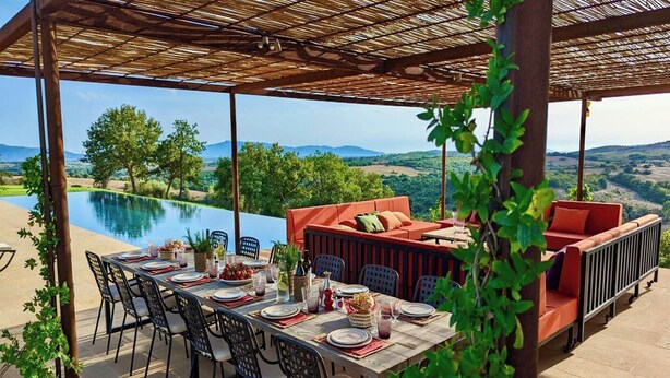 An outdoor dining area with a pool view, a covered seating area, and a table set for a meal. - Maniero in Maremma, luxury villa (Montiano)