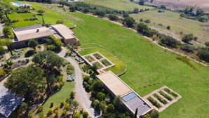 An aerial view of a property with a large green field, a swimming pool, and a building with solar panels. - Maniero in Maremma, luxury villa (Montiano)