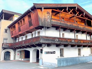 A traditional wooden building with a balcony and a sign indicating it is a parking garage for customers.