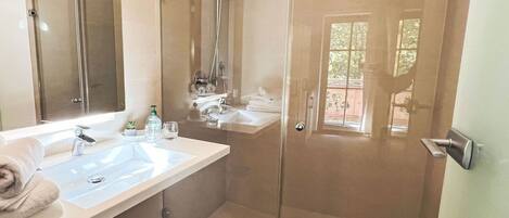 Une salle de bain moderne avec une douche à parois de verre, un grand miroir et un meuble-lavabo avec un évier et un porte-serviettes.