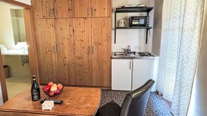 Cozinha compacta com armários de madeira, micro-ondas embutido e uma pia pequena.